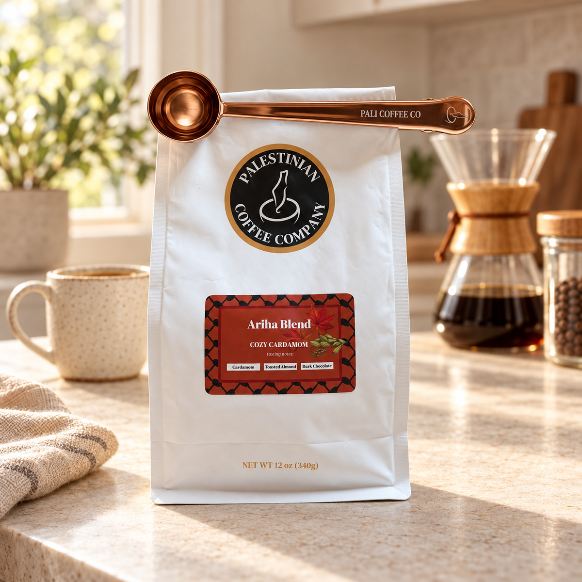 Rose gold Pali Coffee scoop and clip holding an Ariha Blend coffee bag closed in a warm kitchen setting